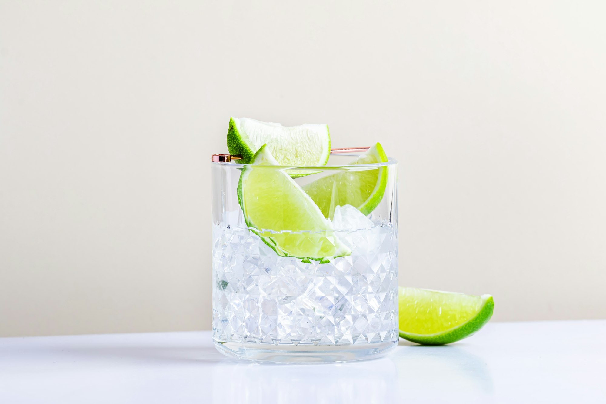 Strong alcoholic cocktail drink with craft rum, sugar syrup and lime. Beige background