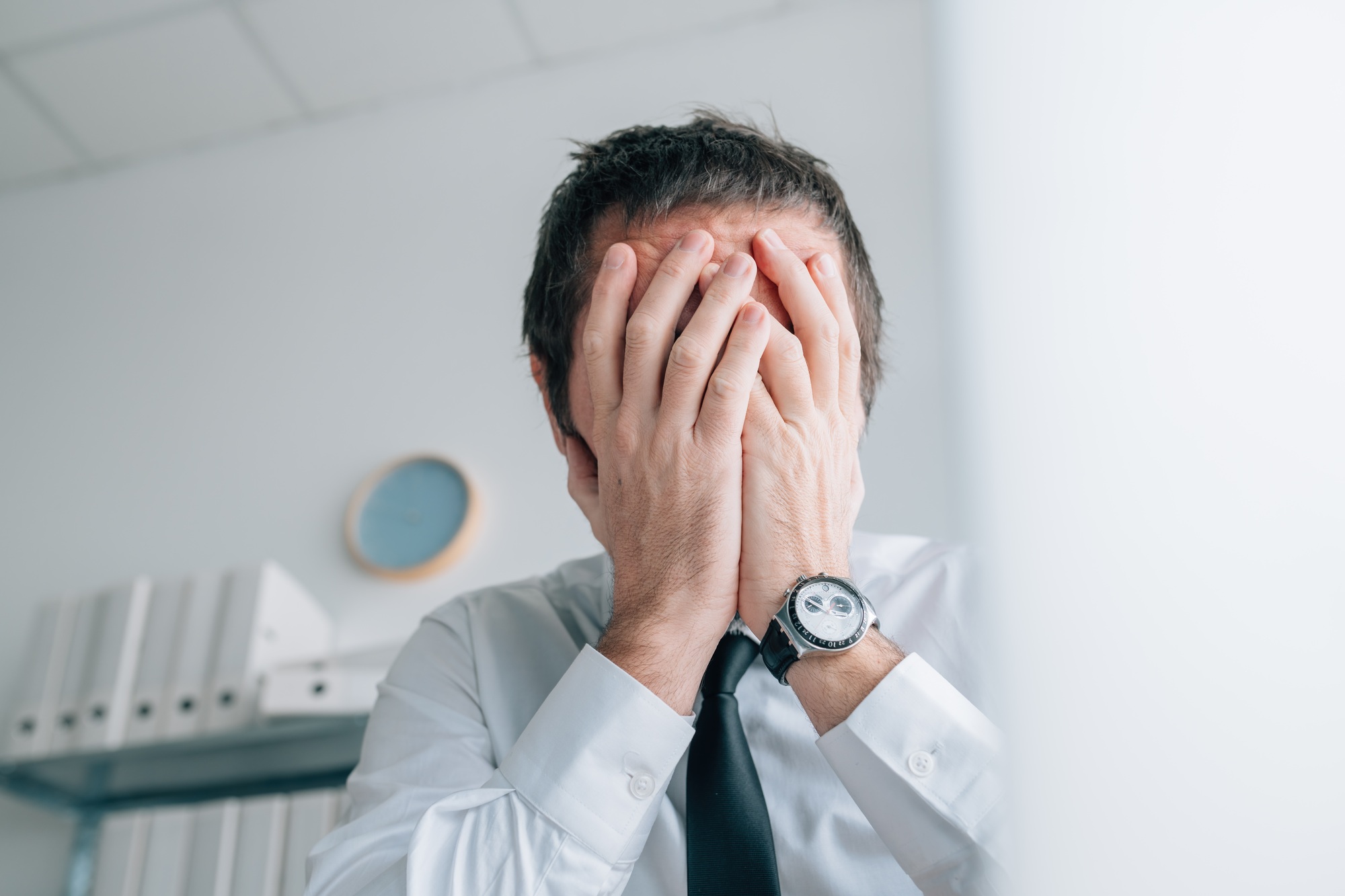Business failure, businessman covering face with hands and crying in office